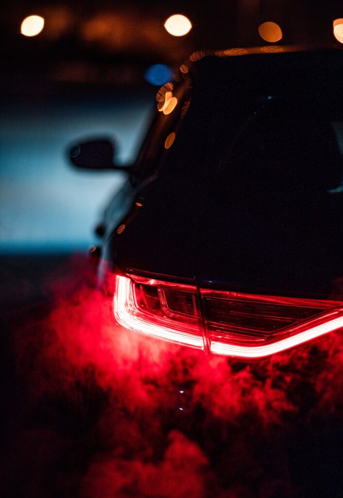 Vertical shot of the smoke coming off the car in the dark street at night